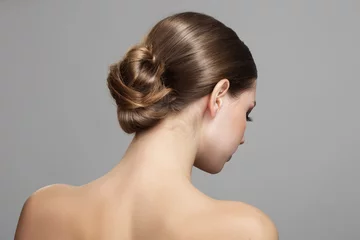 Fotobehang Woman with bun hairstyle on gray background. Bare back, shoulders and neck. Back view © Alena