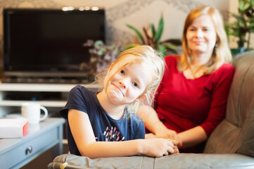 Portrait of cute blond hair little girl and her mother indoor at home