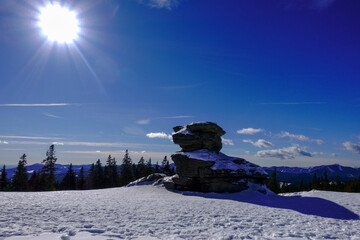 shining sun and a huge rock with snow while hiking