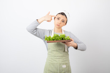 Portrait of a pretty cute woman holding a wooden board with fresh lettuce