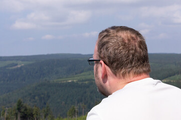 Man with a white t-shirt land glasses looking at the landscape