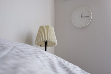 Side view on looking bed in bedroom, with lamp analog alarm clock