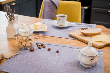 on linen towel on a wooden table, simple breakfast of two mugs of coffee, and slices of bread and cheese