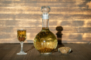 Homemade birch buds tincture in a glass bottle and a wine crystal glass on a wooden table background