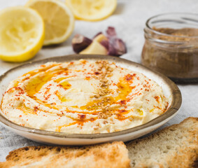 Healthy Homemade Creamy Hummus with the ingredients. Side view. A close-up Mediterranean dish made of chickpea beans