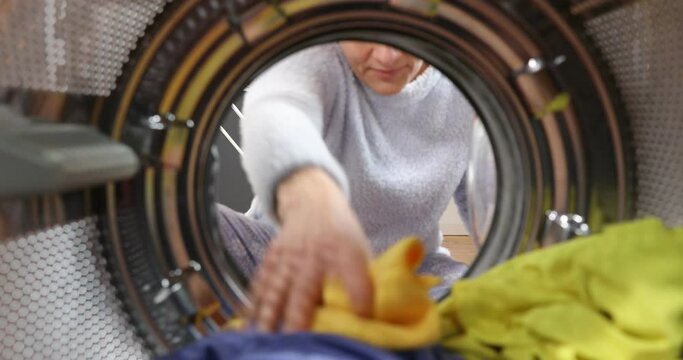 A woman hangs the laundry on the dryer. Housewife Daily Routine. Hanging up washing in a clothes dryer rapid. View Looking Out From Inside Washing Machine.