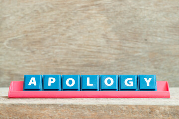 Tile alphabet letter with word apology in red color rack on wood background