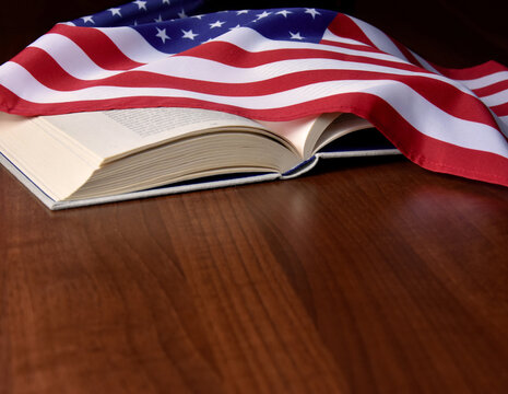 Open book with the American flag on the table frame stock images. American flag with book on a wooden background with copy space for text images