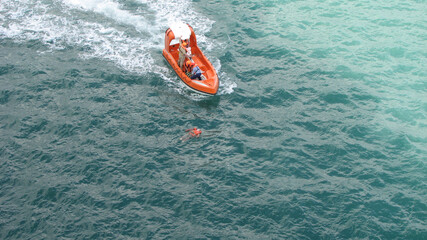 sea rescue boat with man floating in water with life jacket drowning