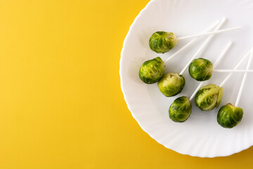 Set of brussel sprouts with lollipop sticks isolated on yellow background	