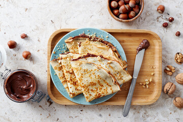 Homemade crepes, tasty thin pancakes with chocolate and nuts. - obrazy, fototapety, plakaty