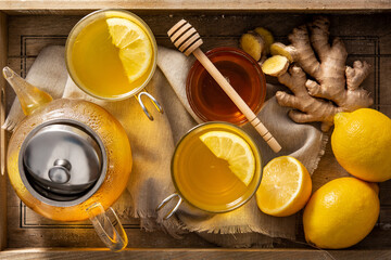 Ginger tea with lemon and honey in crystal glass on a tray. Top view