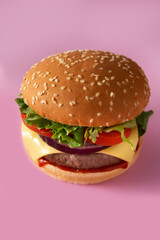 Cheeseburger with beef,tomato, lettuce and onion on pink background