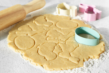 Dough with cookie cutters and rolling pin on kitchen table