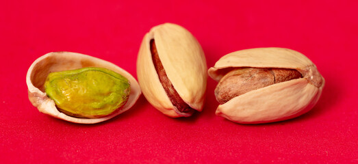 Fototapeta premium Close-up of fresh pistachio nuts on a red background.