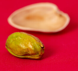 Close-up of fresh pistachio nuts on a red background.