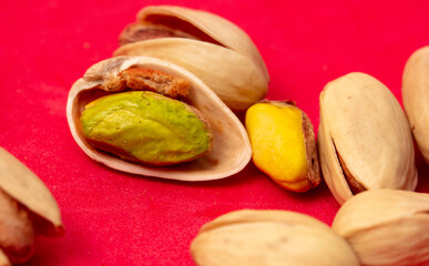 Close-up of fresh pistachio nuts on a red background.