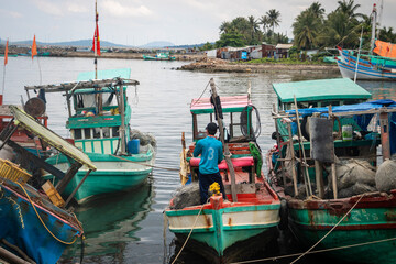 Fototapeta na wymiar an asian adult standing on his fishing boat holding a net to start work day on morning at the island