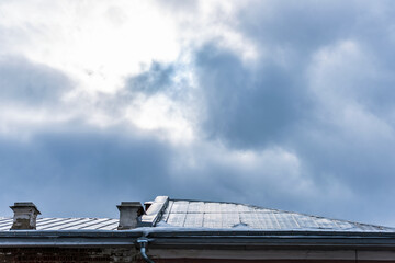 Fototapeta premium Clearance in the cloudy sky above the metal roof of the building.