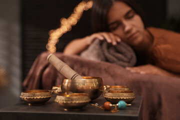 Woman at healing session in dark room, focus on singing bowl