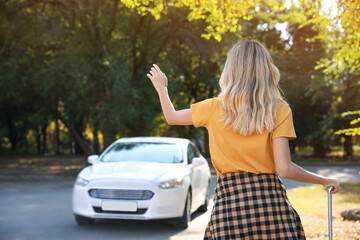 Woman catching taxi on city street, back view