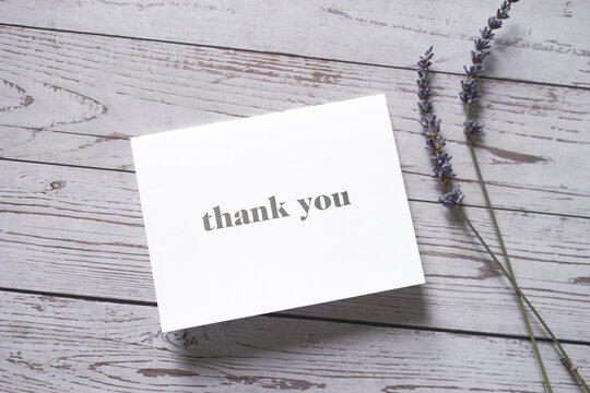 Thank you card on wooden table with a pair of lavender flowers. Elegant minimalist composition. Special thank you note.	
