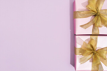 Womens day, 8 march concept. Top view of two small wrapped gift boxes with golden bows on pink background