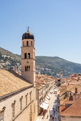 Fototapeta na wymiar Dubrovnik, Croatia - Aug 22, 2020:Stradun street view of Franciscan church bell tower in morning sunrise in morning