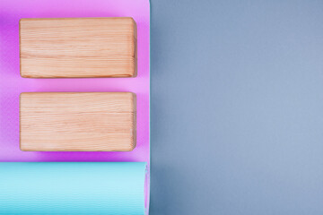 Top view of blue pink yoga mat and two wooden blocks on pastel grey background. Yoga, pilates,...