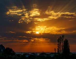 Sunset from Anaxos village over the Aegean sea, golden sunlight rays between the clouds at the end of the day. Vacation holiday on Lesvos an island of Greece.