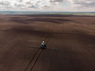 Spring agricultural work in the fields. The tractor sprays crops with herbicides, insecticides and pesticides.