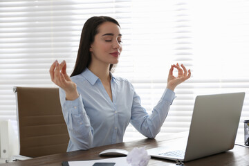 Businesswoman meditating at workplace in office. Stress relieving exercise