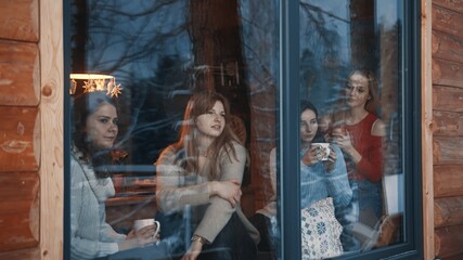 Group of young women having fun in the mountain wooden house surrounded by snow. High quality photo