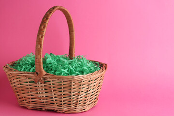 Fototapeta na wymiar Easter basket with green paper filler on pink background, space for text