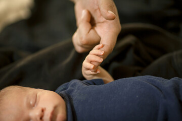 a newborn baby is sleeping, holding his father's finger. close-up of the hand