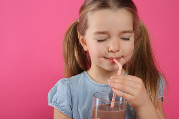 Cute little child drinking tasty chocolate milk on pink background. Space for text