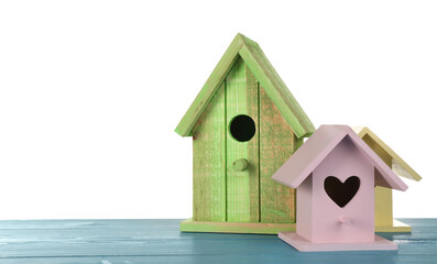 Obraz na płótnie Canvas Three different bird houses on light blue wooden table against white background