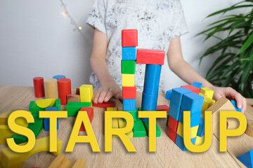 child, kid plays with colored wooden cubes, builds rocket, startup concept, business ideas of the...