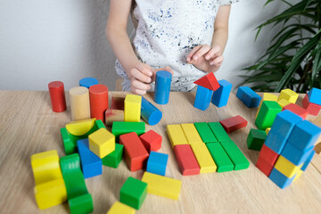child, kid plays with colored wooden cubes, builds houses and rockets, concept of development of fine motor skills, tactile sensations, creativity, children's entertainment