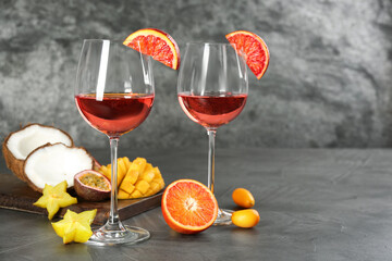 Delicious exotic fruits and wine on grey table
