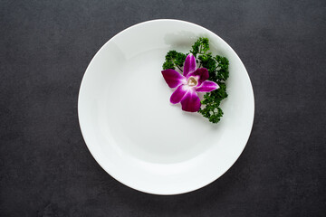 White empty plate decorated with orchids and parsley