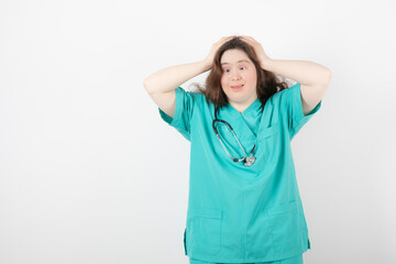 Young female doctor with down syndrome standing on white background