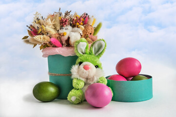 Soft toy green rabbit, beautiful bouquet of dried flowers and colorful painted natural chicken eggs.