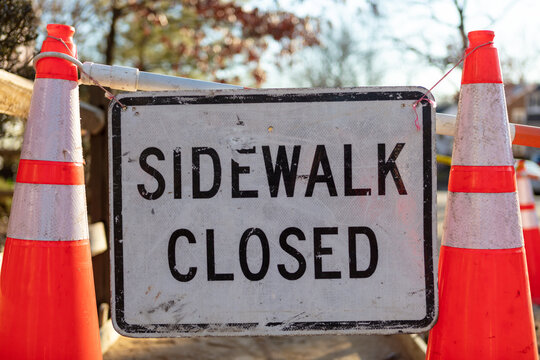 Dirty worn Grunge covered Sidewalk Closed Sign between two traffic cones