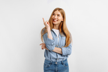 young woman points finger up in copy space while standing over white background