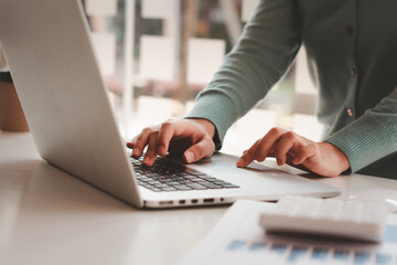 Business woman working and typing on laptop computer on the table.