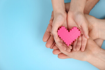 Top view of parents and kid holding pink heart in hands on turquoise background, space for text. Family day