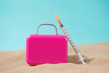 syringe and suitcase on the sand
