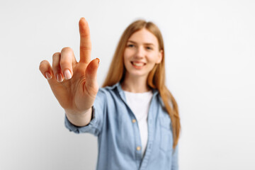 Attractive young woman pressing virtual button over white background