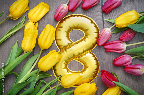 8 March, International Women's Day. Figure eight of with beautiful yellow and red tulips on wooden background.